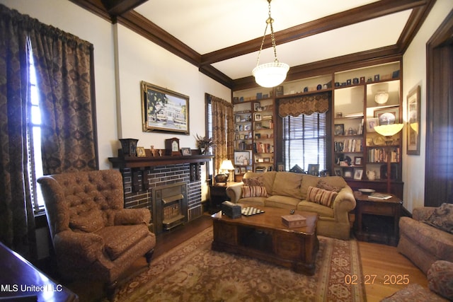 living room featuring a brick fireplace, crown molding, beamed ceiling, and wood finished floors