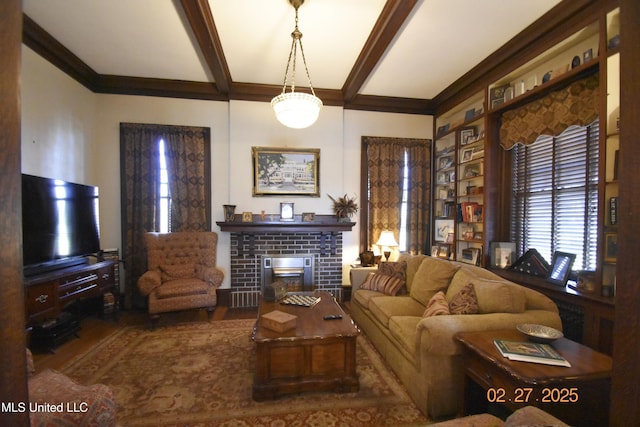 living area with a brick fireplace, beamed ceiling, and wood finished floors