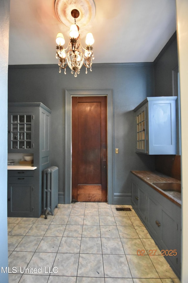 kitchen with light tile patterned flooring, crown molding, and radiator heating unit