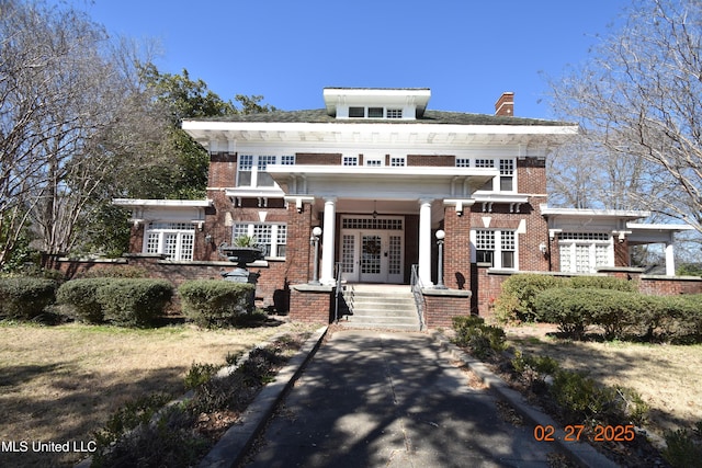 view of front of home with french doors, a chimney, and brick siding