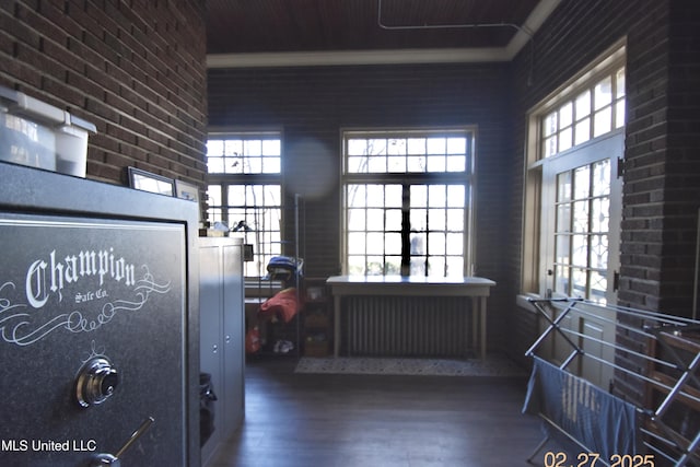 misc room featuring brick wall, wood finished floors, and a towering ceiling