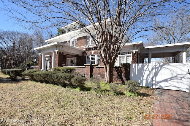 view of side of home featuring a fenced front yard and brick siding