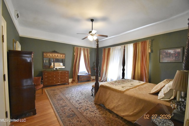 bedroom with a ceiling fan, visible vents, crown molding, and wood finished floors