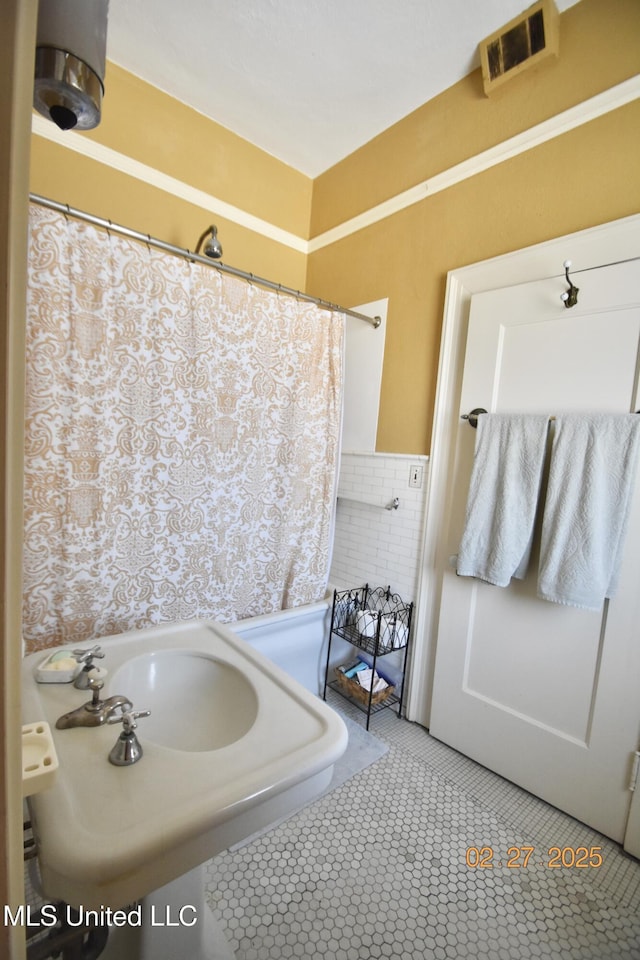 full bathroom featuring a wainscoted wall, tile patterned flooring, visible vents, and tile walls