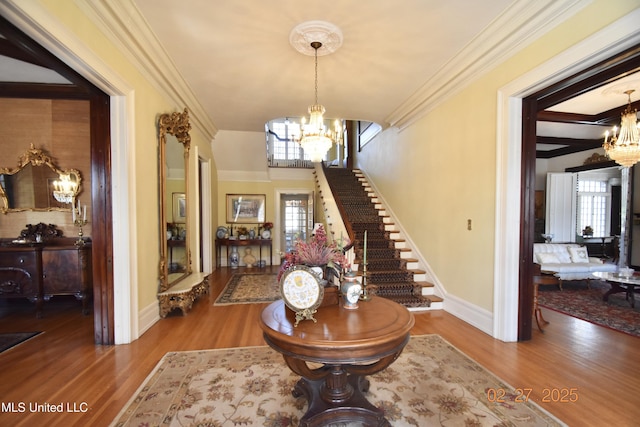 foyer featuring ornamental molding, wood finished floors, stairway, and an inviting chandelier