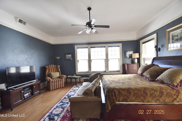 bedroom with a ceiling fan, visible vents, and wood finished floors