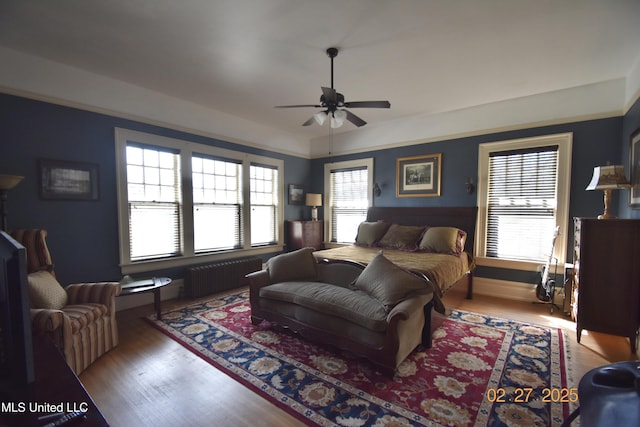 bedroom featuring radiator heating unit, ceiling fan, and wood finished floors