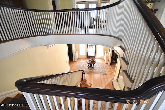 stairway featuring arched walkways, a high ceiling, and wood finished floors