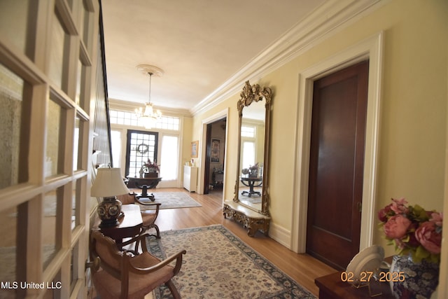 foyer with an inviting chandelier, baseboards, crown molding, and wood finished floors