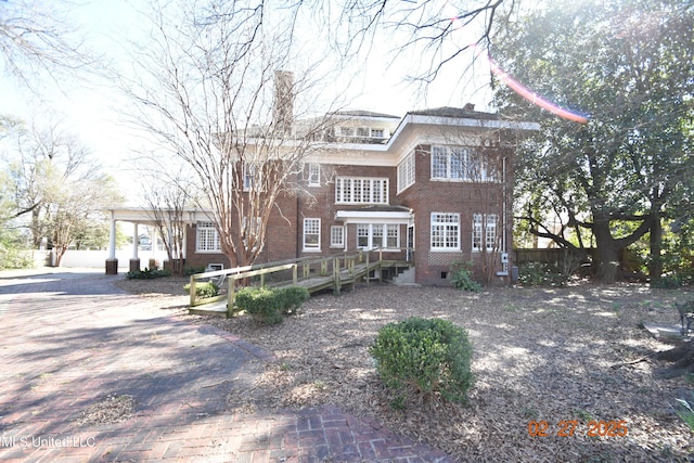 view of front of property with brick siding, a chimney, and fence