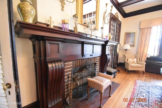 sitting room featuring ornamental molding, a brick fireplace, and wood finished floors