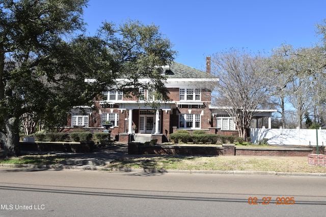 view of front of home with french doors, fence, and brick siding