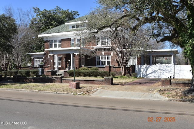 view of front of property featuring driveway, brick siding, and fence