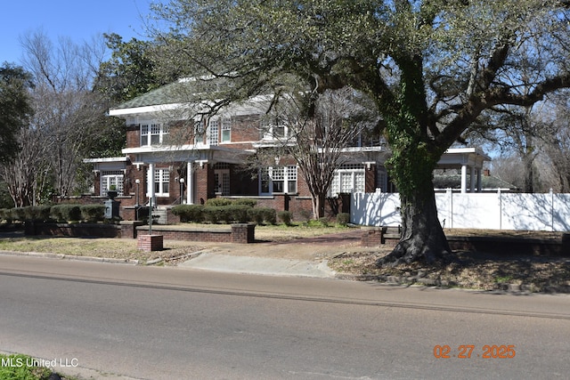 view of front facade featuring brick siding and a fenced front yard