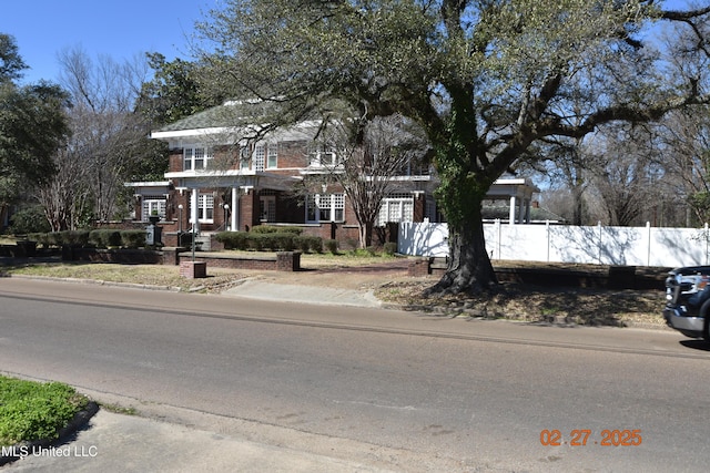 view of front of house featuring brick siding and fence