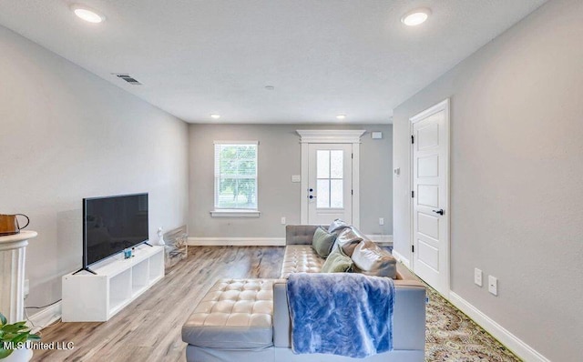 living room featuring baseboards, visible vents, wood finished floors, and recessed lighting