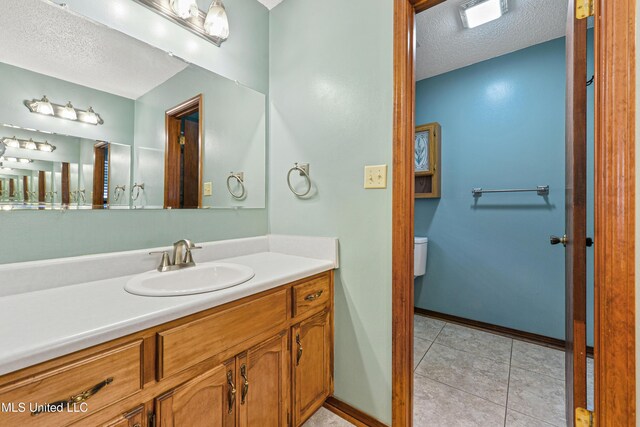 7300 Frank Snell Rd, Moss Point, MS 39562 - bathroom featuring a textured ceiling, vanity, tile patterned flooring, baseboards, and toilet