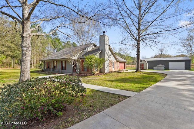 7300 Frank Snell Rd, Moss Point, MS 39562 - view of front facade featuring covered porch, an outdoor structure, a detached garage, a chimney, and a front yard