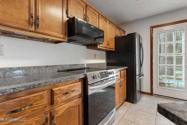 7300 Frank Snell Rd, Moss Point, MS 39562 - kitchen featuring black microwave, stainless steel electric range oven, brown cabinetry, light tile patterned floors, and a textured ceiling