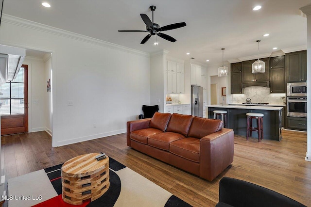 living room with hardwood / wood-style flooring, ceiling fan, and ornamental molding