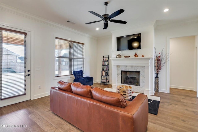 living room with ceiling fan, a fireplace, hardwood / wood-style floors, and ornamental molding