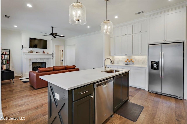 kitchen featuring white cabinets, stainless steel appliances, a kitchen island with sink, and sink