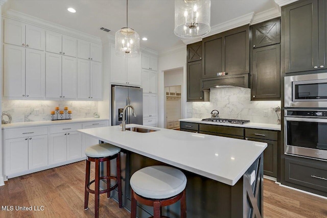 kitchen with decorative backsplash, a center island with sink, and stainless steel appliances