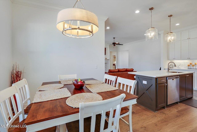 dining room featuring crown molding, sink, ceiling fan with notable chandelier, and light hardwood / wood-style flooring