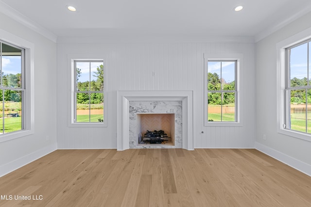 unfurnished living room with crown molding, light hardwood / wood-style flooring, and a wealth of natural light