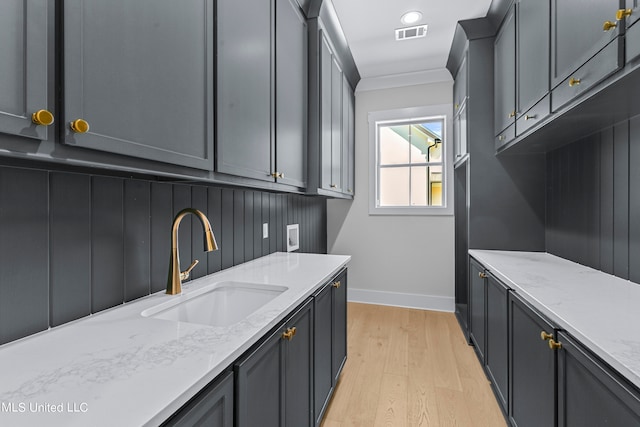 kitchen featuring gray cabinets, sink, light wood-type flooring, and light stone counters