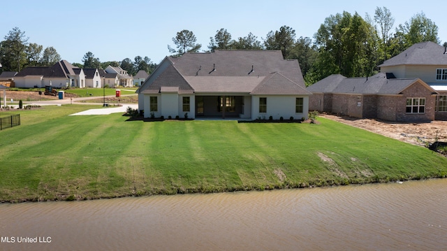 rear view of property with a patio area, a water view, and a lawn