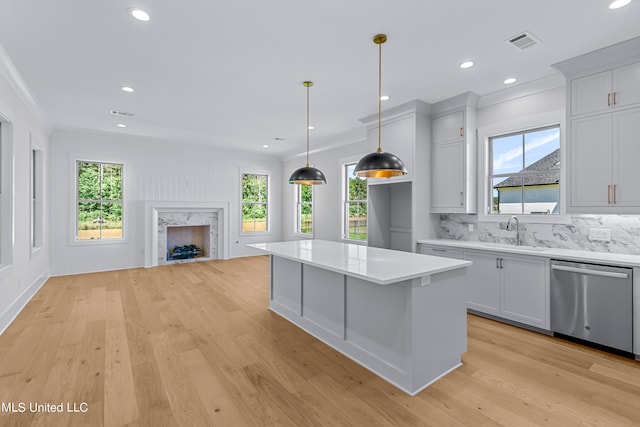 kitchen with a kitchen island, plenty of natural light, light hardwood / wood-style floors, pendant lighting, and stainless steel dishwasher