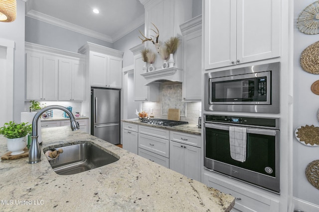 kitchen with sink, crown molding, appliances with stainless steel finishes, light stone counters, and white cabinets