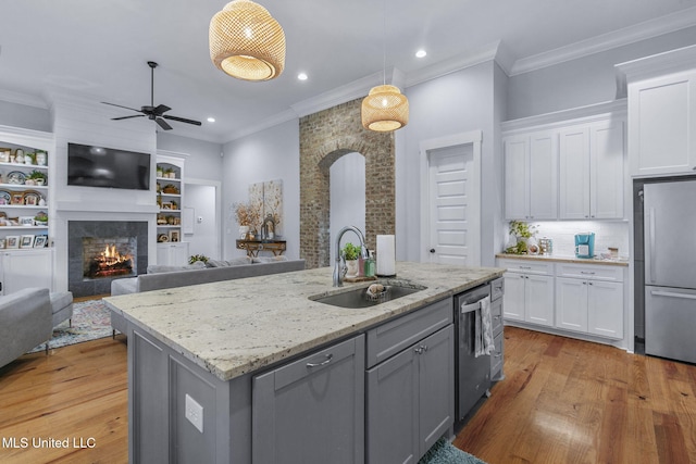 kitchen featuring a kitchen island with sink, pendant lighting, stainless steel appliances, and white cabinets