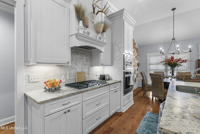 kitchen featuring stainless steel appliances, sink, white cabinets, and decorative light fixtures