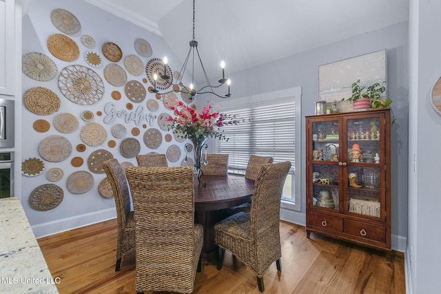 dining room with a notable chandelier, lofted ceiling, and light wood-type flooring