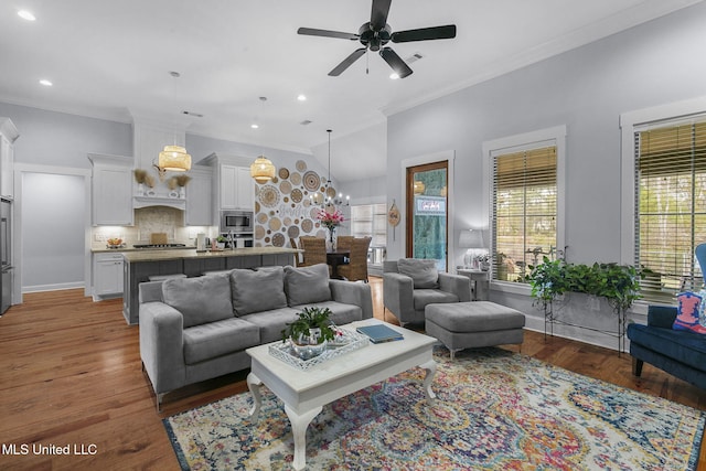 living room with dark wood-type flooring, crown molding, and ceiling fan with notable chandelier