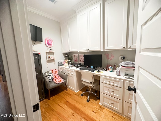 office with crown molding, built in desk, and light wood-type flooring