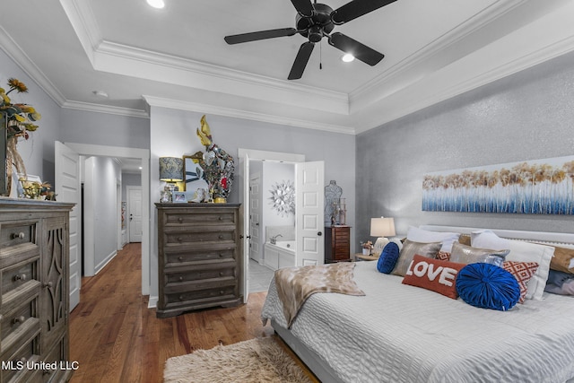 bedroom featuring ensuite bath, ceiling fan, hardwood / wood-style floors, a tray ceiling, and ornamental molding