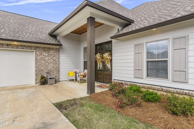 view of exterior entry with a garage, french doors, and a patio area