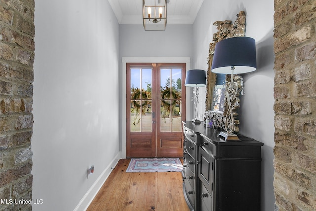 entrance foyer featuring crown molding, wood-type flooring, an inviting chandelier, and french doors