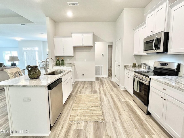 15681 Perdido Dr, Gulfport, MS 39503 - kitchen with stainless steel appliances, a sink, light wood-style flooring, white cabinets, and light stone counters