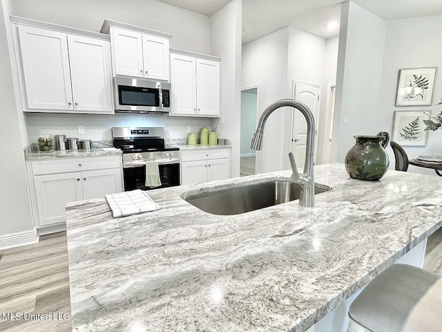 15681 Perdido Dr, Gulfport, MS 39503 - kitchen with stainless steel appliances, white cabinets, a sink, and light wood-style flooring