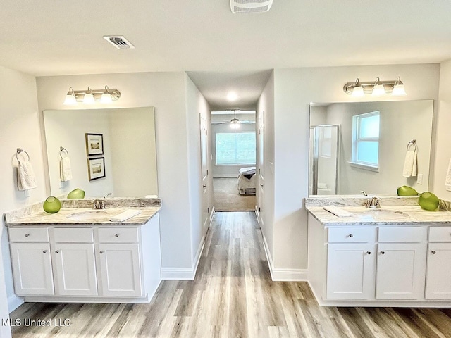 15681 Perdido Dr, Gulfport, MS 39503 - full bathroom with wood finished floors, a shower stall, two vanities, and baseboards