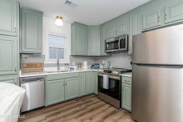 kitchen featuring a sink, visible vents, light countertops, green cabinets, and appliances with stainless steel finishes