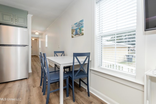 dining room with baseboards, light wood finished floors, and crown molding