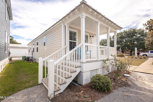 property entrance with cooling unit, a yard, and a porch