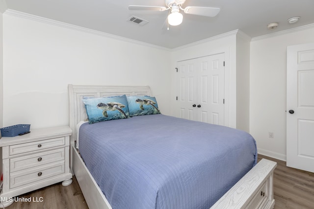 bedroom featuring a closet, crown molding, dark wood finished floors, visible vents, and ceiling fan