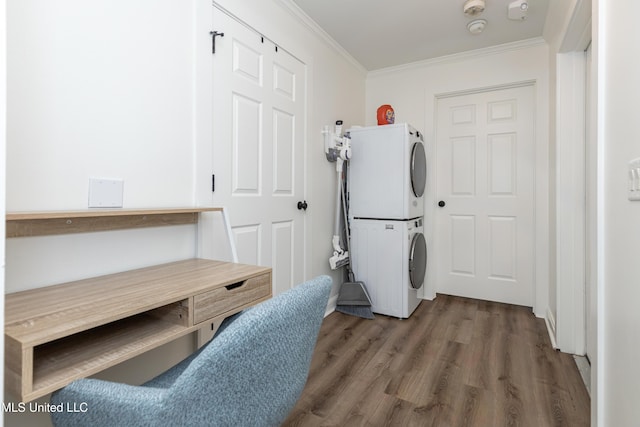 laundry room with ornamental molding, laundry area, stacked washer / drying machine, and wood finished floors