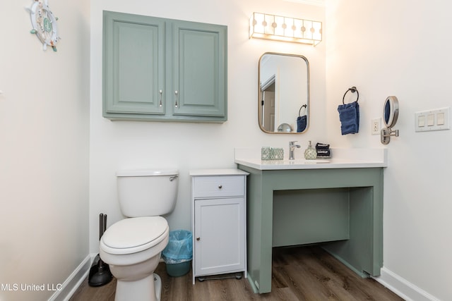bathroom featuring toilet, baseboards, wood finished floors, and vanity